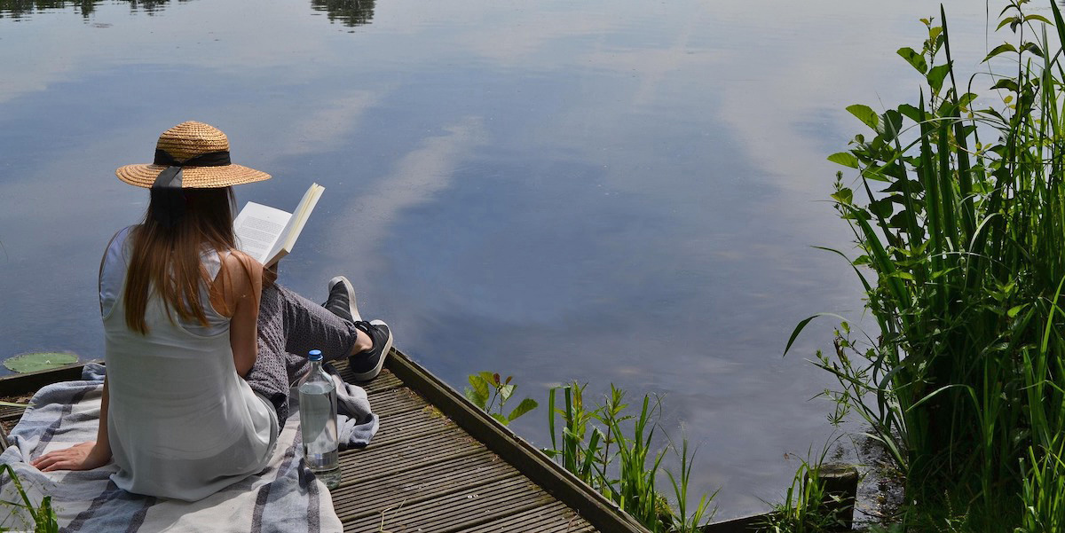 woman sitting on dock and reading a book